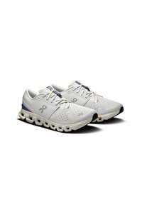 Lightweight white athletic shoes with textured mesh upper, navy accents, and distinctive cloud-like sole design. Black toe cap detail visible.