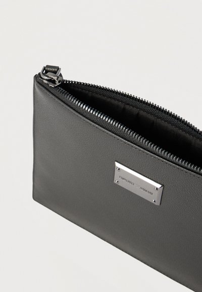 Μαύρο δερμάτινο τσαντάκι με φερμουάρ και ασημένια πλακέτα με το λογότυπο Emporio Armani στο μπροστινό μέρος, μισάνοιχτο που αποκαλύπτει το λείο εσωτερικό ύφασμα.