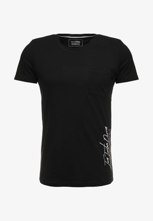 T-shirt noir à manches courtes et col rond avec une petite poche sur la poitrine et un texte blanc en cursive imprimé verticalement en bas à droite.
