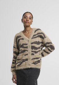 Bežn fuzzy kardigan z temno rjavim živalskim vzorcem, z V-izrezom, gumbom za zapiranje in dolgimi rokavi. Mehka tekstura in udoben kroj.