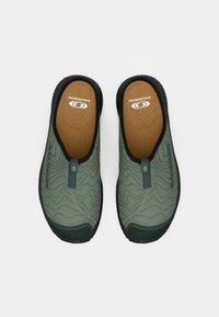 Grønne slip-on sko med strukturert overdel, svarte detaljer og korkinnersåle. Har en fleksibel gummisåle og en draflik for enkel påkleding.