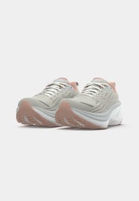 Zapatillas deportivas gris claro con un upper texturizado, acentos en rosa y una suela blanca gruesa, con perforaciones y una banda de rodadura de goma de contraste.