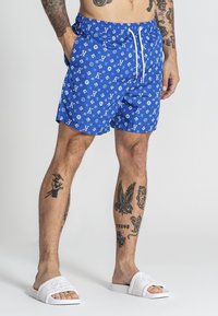 Blå simshorts med ett upprepat vitt mönster, elastisk midja med dragsko och sidofickor.