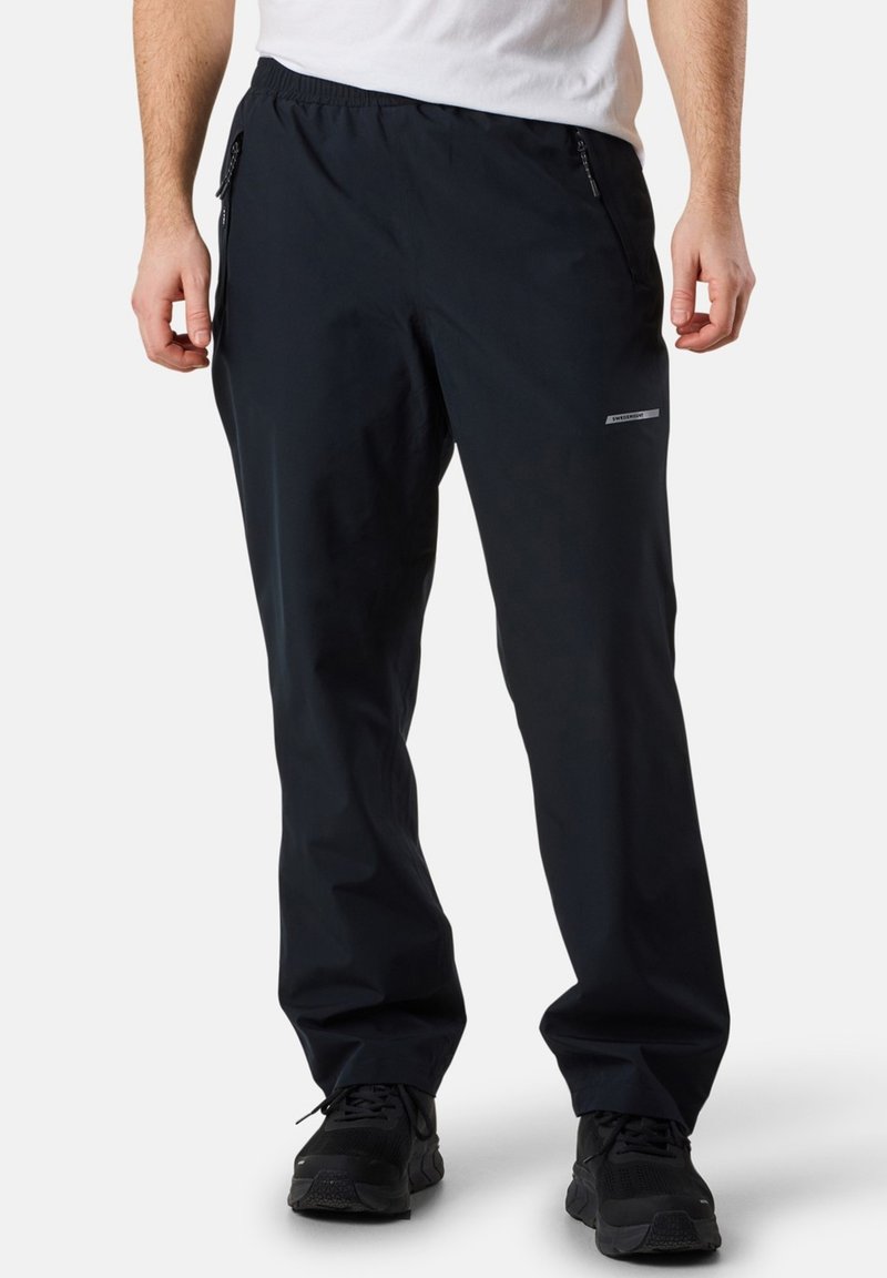 Schwarze wasserdichte Hose mit elastischem Bund, seitlichen Reißverschlusstaschen und lockerer Passform, aus leichtem, atmungsaktivem Material.