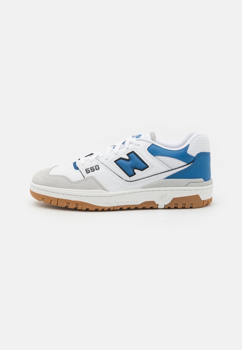 Baskets New Balance 550 blanches et bleues avec semelle en gomme, bout en daim gris et panneaux latéraux perforés, vues du côté extérieur.