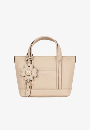 Beige leather tote handbag with double handles and a stitched flower-shaped keychain attached to the front left handle.