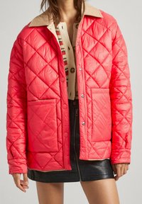 Chaqueta acolchada de color coral brillante con un cuello de color caramelo, con cierres de botones y dos bolsillos delanteros. Las superficies son lisas con una textura ligera.