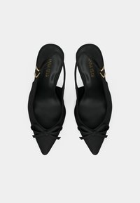 Black pointed slingback flats with small bows and gold buckle accents, viewed from above on a plain white background.