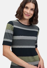 Haut tricot à manches courtes présentant des rayures alternées en marine, olive et blanc avec un motif texturé et un col rond.