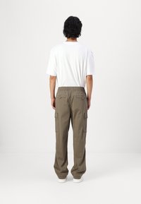 Kaki cargobyxor med elastisk midja, sidofickor och en avslappnad passform, kombinerat med en enkel vit t-shirt.