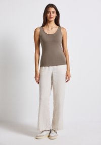 Brun tanktop med en rund halsudskæring, parret med løse, cremefarvede linnedbukser og lyse sneakers. Enkel design og neutrale farver.