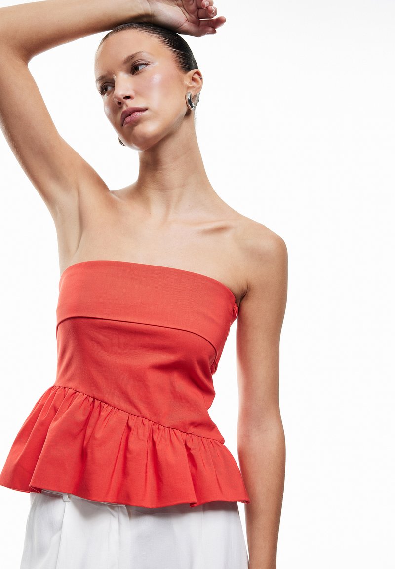 Rød strapless peplum-top med tætsiddende overdel og volangnederdel. Fremstillet af letvægtsstof, der har en glat tekstur og et enkelt design.