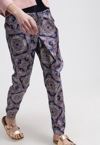 Navy blue patterned pants featuring intricate paisley designs in purple and silver. Lightweight fabric with an elastic waist and relaxed fit.