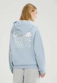 Sudadera con capucha azul y logo de texto blanco en la parte posterior. Tejido suave, corte relajado, puños y dobladillo acanalados. Con costuras laterales.