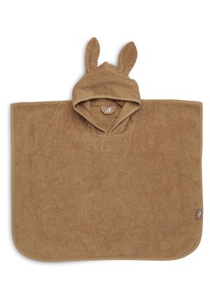 Poncho marron à capuche fabriqué en tissu doux et texturé avec des oreilles de lapin. Présente un ourlet incurvé et une étiquette en bas à droite.