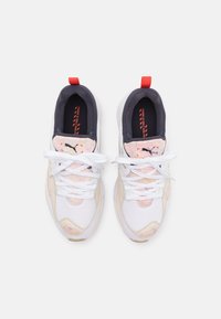 Paire de baskets Puma blanches et beiges avec accents multicolores, lacets blancs, intérieurs noirs et languettes rouges, vues de dessus sur fond blanc.