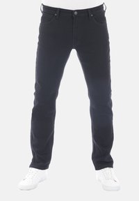 Vaqueros negros de denim, corte recto, cintura media, diseño de cinco bolsillos, con cierre de botón y cremallera, combinados con zapatillas blancas.