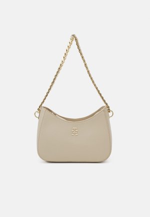 Beige leren handtas met een gouden gedraaide kettingriem en een klein gouden logo-embleem in het midden van de voorkant.