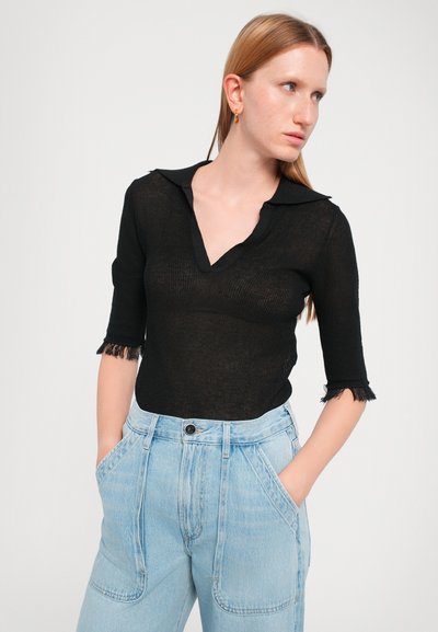 Black knit top with a collar, three-quarter sleeves featuring frayed edges. Paired with light blue high-waisted jeans, accentuating a relaxed fit.