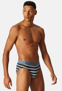 Brief a righe realizzato in tessuto morbido, con un elastico blu e una base blu navy con righe bianche e grigie chiare. Nessun motivo o accento aggiuntivo.