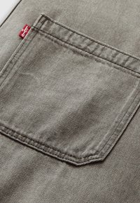 Gray denim back pocket with double-stitching and a small red fabric Levi's tag on the left side seam.