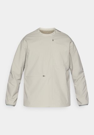 Hellbeige Jacke aus wasserabweisendem Material. Mit langen Ärmeln, Rundhalsausschnitt und einer Vordertasche mit Reißverschluss.