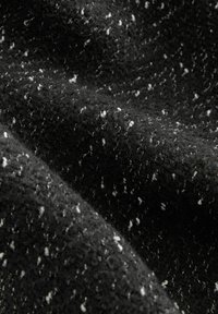 Czarna wełniana tkanina o teksturowanym, pętelkowym wzorze z rozrzuconymi białymi plamkami tworzącymi efekt cętkowany.