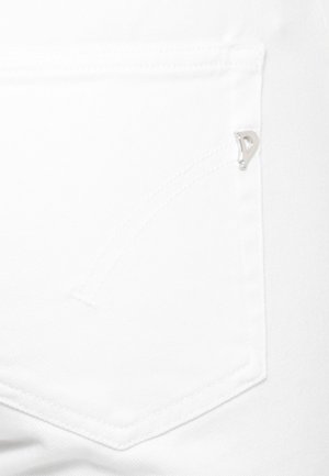 Primo piano della tasca in denim bianco con una piccola targhetta metallica argentata nell'angolo in alto a destra e un sottile dettaglio di cuciture curve.