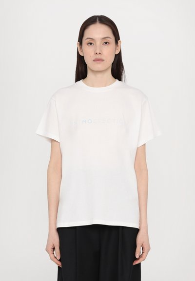 Λευκό βαμβακερό T-shirt με κοντά μανίκια, που έχει τη λέξη "INTROSPECTION" σε διακριτική μπλε γραφή στο στήθος. Απλή, άνετη εφαρμογή.