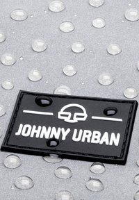 Fekete téglalap alakú folt fehér felirattal, melyen a "JOHNNY URBAN" felirat olvasható, egy érdes ezüst felszínen vízcseppekkel.