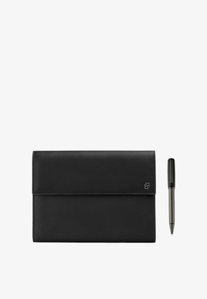 Étui folio en cuir noir avec un petit logo métallique sur le rabat, posé à côté d'un stylo noir et argenté sur un fond blanc.
