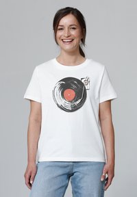 T-shirt en coton blanc avec un graphique de disque vinyle noir au centre rouge et des détails de stylo, à manches courtes et à coupe standard.