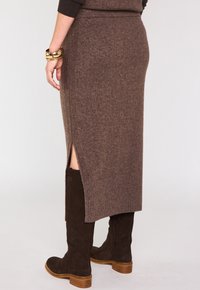 Jupe midi en tricot marron avec fentes latérales, ourlet côtelé, associée à des bottes en suede marron au genou avec un talon empilé.