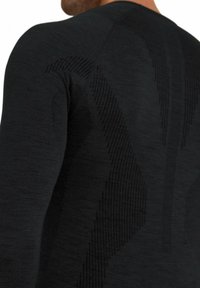 Zwarte, aansluitende longsleeve top met textuurpatronen en contrasterende ribbels op de rug, gemaakt van een lichte, gladde stof.