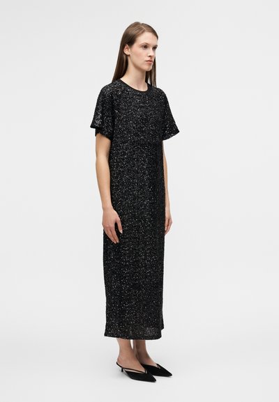 Μαύρο, λαμπερό midi φόρεμα με κοντά μανίκια, στρογγυλή λαιμόκοψη και ίσια σιλουέτα. Συνδυασμένο με μαύρα μπαλαρίνες με μύτη.