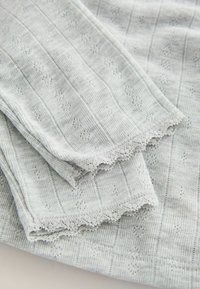 Grauer Strickstoff mit vertikalen Streifen und kleinen Blumenmustern. Die Kanten sind mit zarter Spitze verziert. Weiche Textur, leichtes Design.