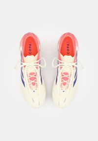 Witte voetbalschoenen met roze accenten en blauwe strepen. Kenmerkt zich door een textuurdesign, platte veters en een merkinsole met het label "COPA."
