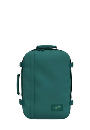 Zaino in tessuto teal di forma rettangolare, con manico superiore, chiusura con zip e patch logo. Texture liscia con cinturini laterali.