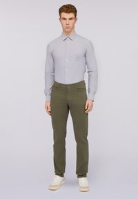 Camisa de manga larga gris claro con cuello, bolsillo frontal y detalles bordados. Pantalones ajustados verde oliva con bolsillos laterales y cierre de botón.