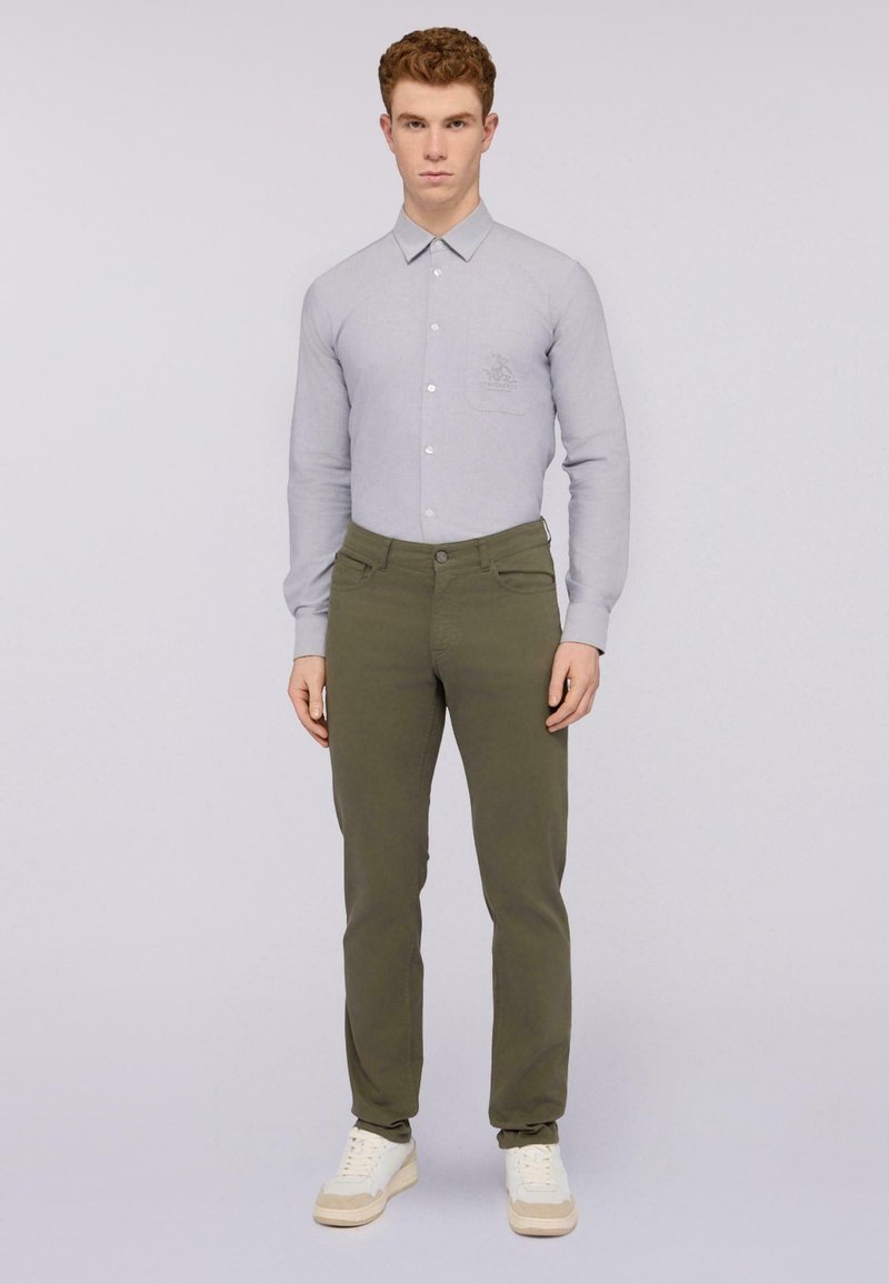 Camisa de manga larga gris claro con cuello, bolsillo frontal y detalles bordados. Pantalones ajustados verde oliva con bolsillos laterales y cierre de botón.