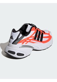 Pantofii sport albi cu accente negre, detalii neon portocalii, partea superioară din plasă, talpă texturată și design curbat distinctiv. Ușori și respirabili.