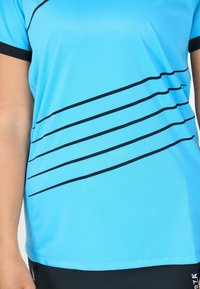 Ljusblå idrottströja med svarta diagonala ränder, korta ärmar och rundad halsringning. Tillverkad av ett mjukt, andningsbart tyg.