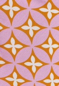 Textiel met een geometrisch patroon van roze en oranje vormen met witte bloemaccenten, wat zorgt voor een gestructureerd, hedendaags ontwerp.