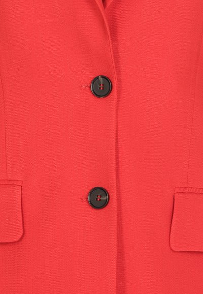 Blazer rosso con tessuto strutturato, caratterizzato da due bottoni neri e due tasche a toppa. Vestibilità sartoriale con una texture liscia.