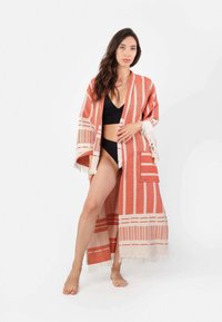 Dolga, lahka kimono v koralni in kremni barvi s črtastim vzorcem, frfotavimi detajli in dvema sprednjima žepoma. Nosi se preko črnega bikini kupa.