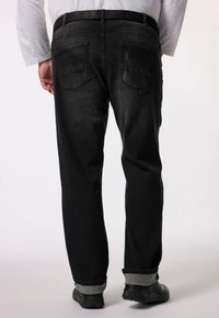 Pantalones de mezclilla negra con un corte relajado, que cuentan con bolsillos traseros, un dobladillo enrollado y una textura suave.