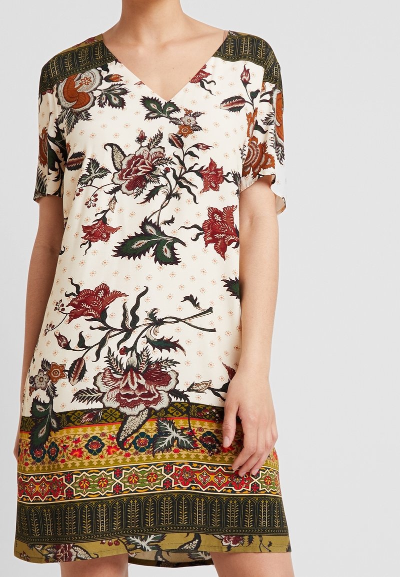 Robe à manches courtes avec un col en V, ornée de motifs floraux rouges, verts et dorés sur un fond clair et une bordure à motifs.