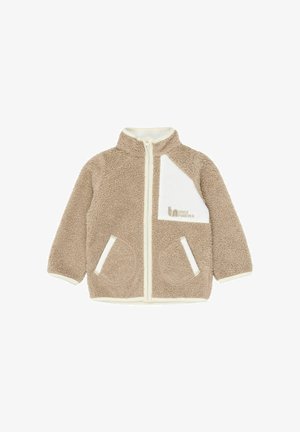Veste polaire beige avec un col montant, une fermeture éclair blanche, une poche poitrine blanche et deux poches latérales. Caractéristiques une texture douce et des accents contrastés.