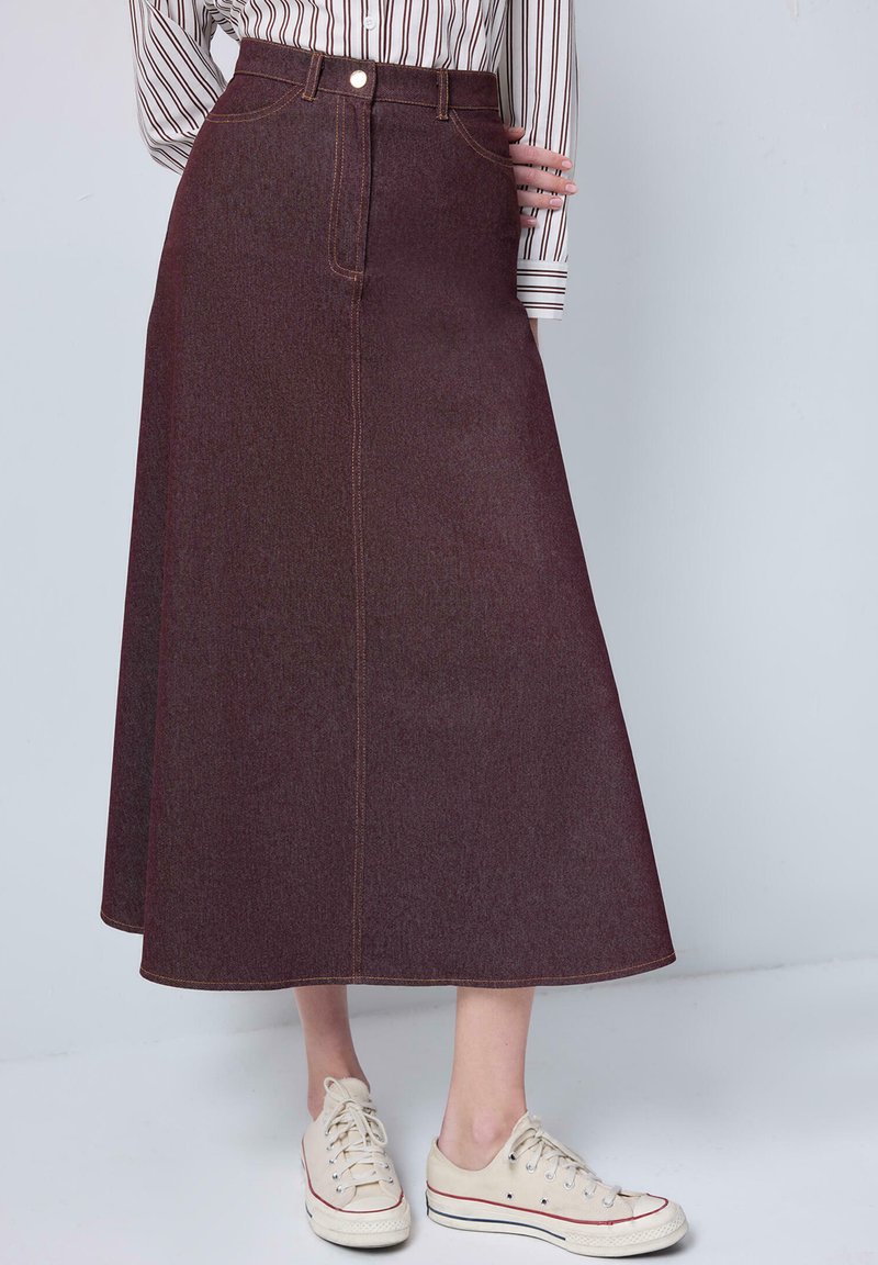 Burgundy denim midi kjol med en lätt A-linjeform, framfickor och kontrasterande gula sömmar. Matchas med beige låga sneakers.