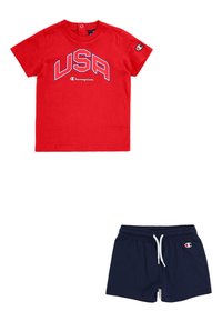 Camiseta de algodón roja con la inscripción "USA" en texto azul y un pequeño logo en la manga, combinada con pantalones cortos azul marino con cinturilla elástica.